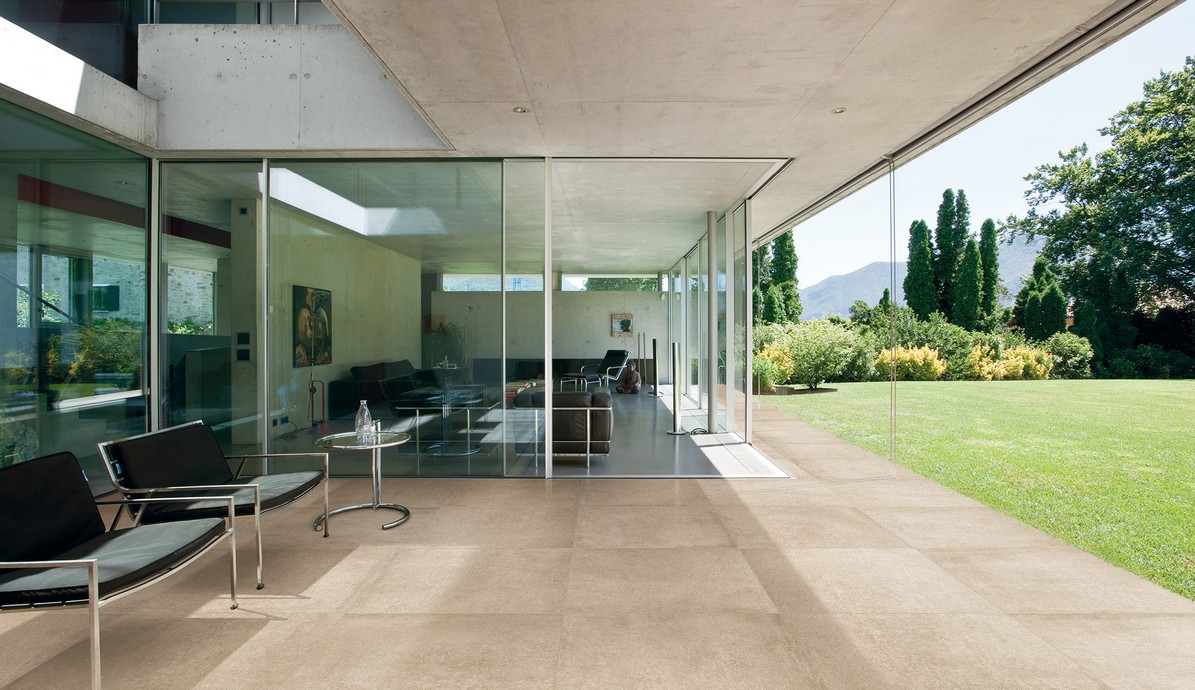 Wohnzimmer mit Glaswänden und Blick auf eine grüne Gartenterrasse