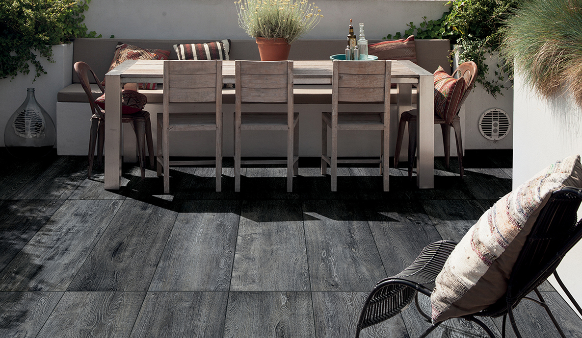 Terrasse mit Holztisch, Stühlen und üppiger Pflanzenwand